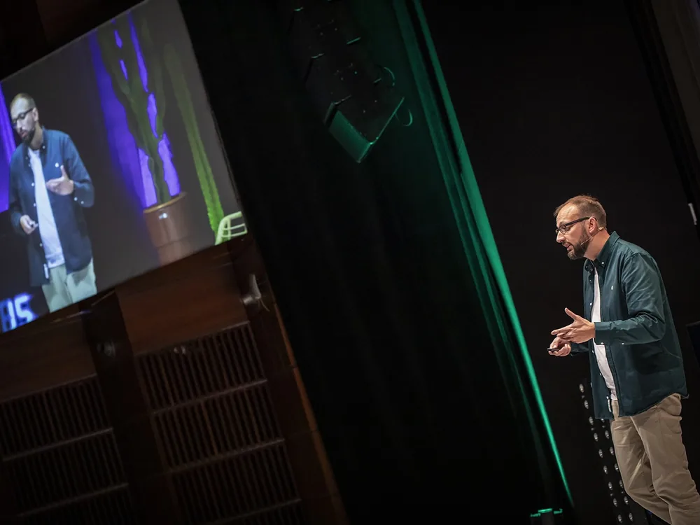 Nicolas François on stage at the Rencontres nationales du e-tourisme in Pau, his image projected on the big screen
